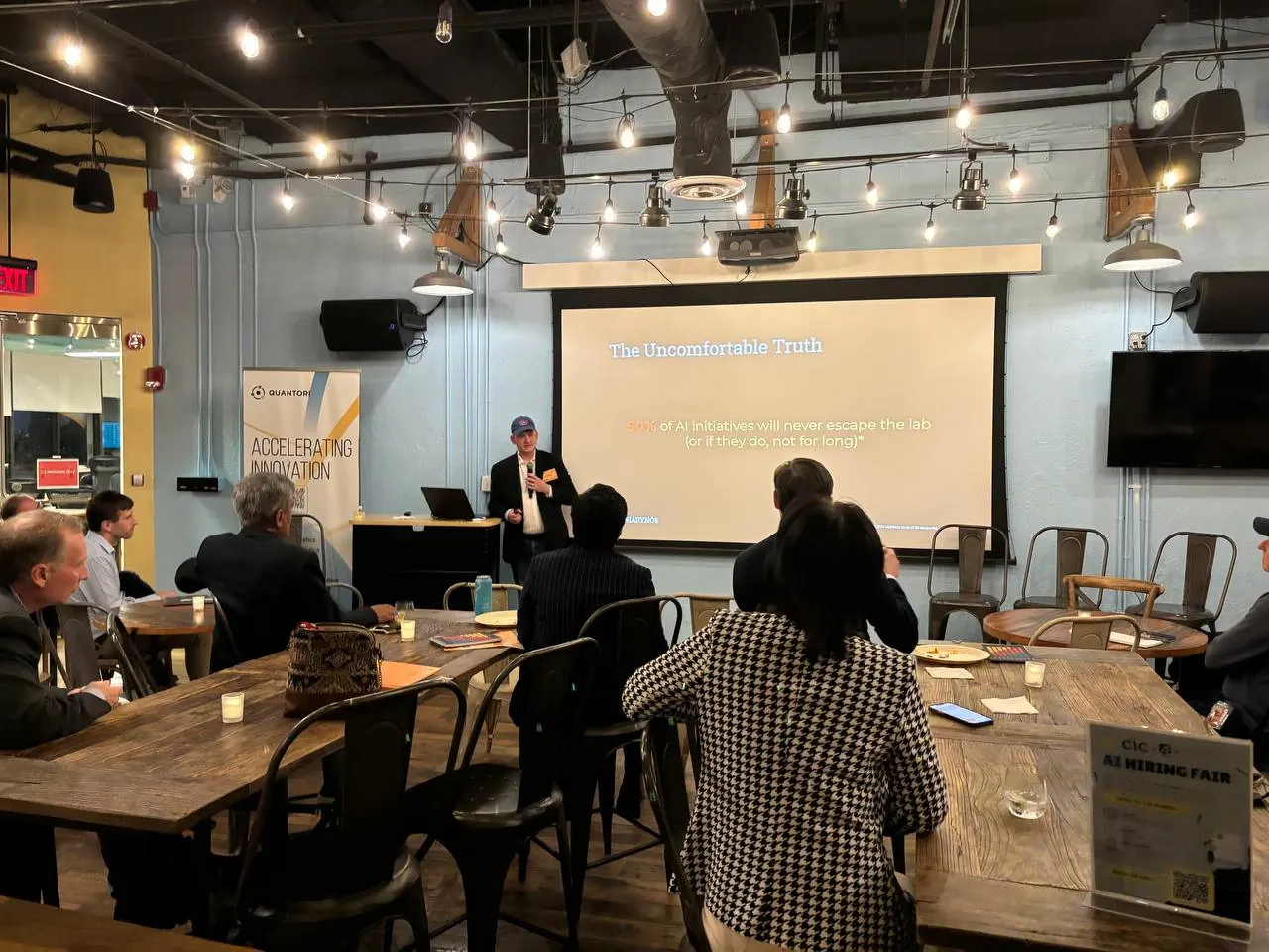 A speaker presenting to guests seated at long tables during a LeadGet workshop